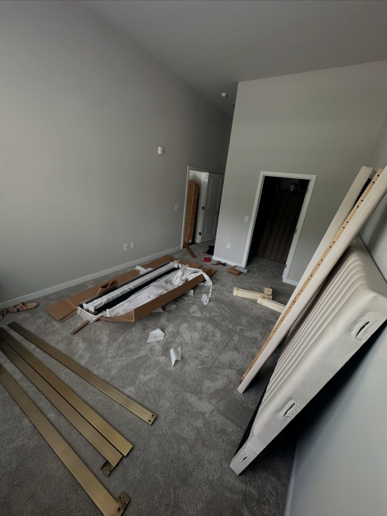 A room with unassembled furniture parts, packaging, and tools, showing assembly service by Mr Capitol Services llc in Laurel, MD.