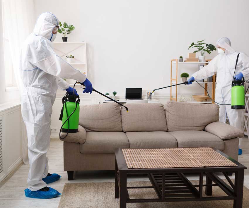 Two cleaners in hazmat suits performing disinfection service in a living room for Core Needs Janitorial in Indianapolis, IN.