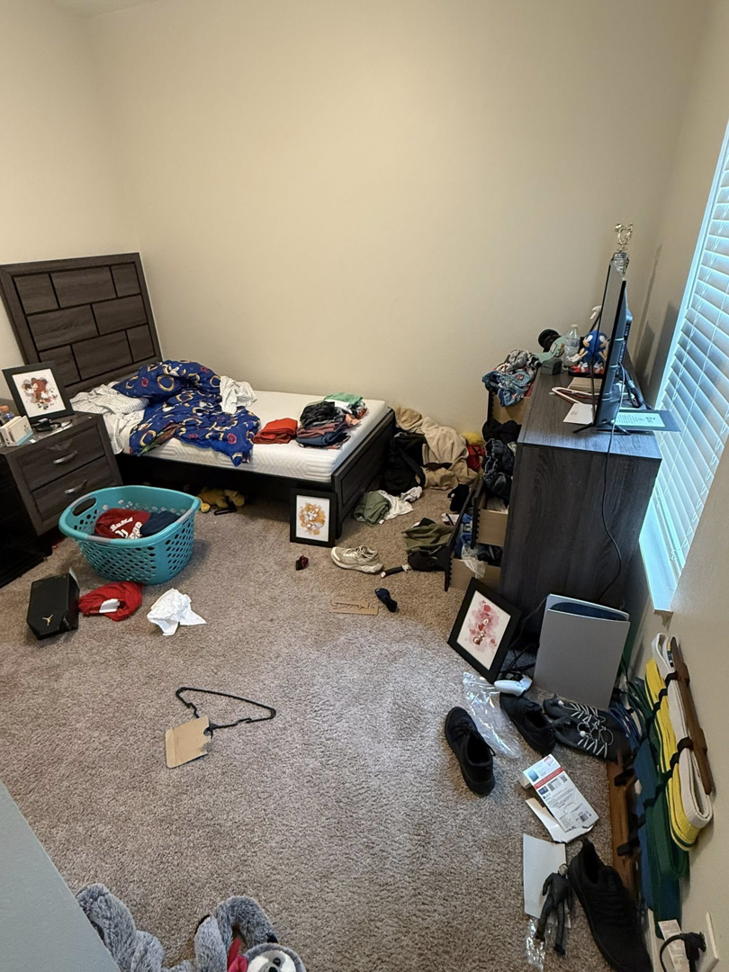 A disorganized bedroom with clothes and items scattered on the floor, before cleaning service by WWJM Cleaning Service in Oklahoma City, OK.