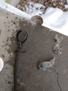 A drain cleaning tool with a large clog of hair and debris removed by Central Wyoming Drain Service in Casper, WY.