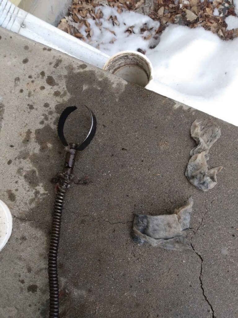 A drain cleaning tool with a large clog of hair and debris removed by Central Wyoming Drain Service in Casper, WY.