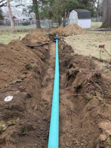 A blue drainage pipe being installed in a trench by Fleury Dirt Works & Services Llc in Cumberland, RI
