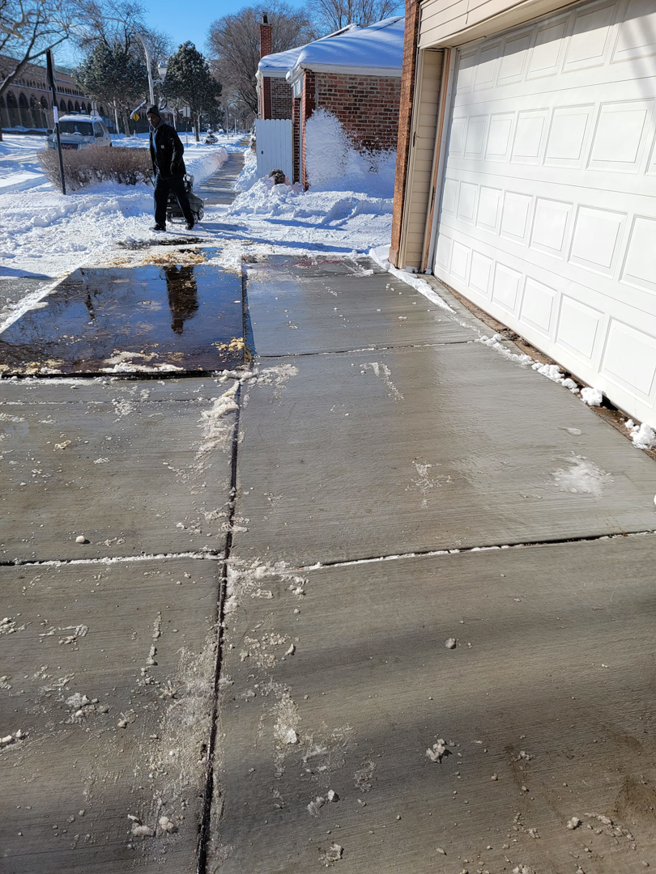 A cleared driveway and sidewalk area next to a garage after snow removal by Apolonio's Snow Removal and Lawn care in Chicago, IL.