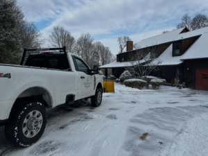 A snow plow truck clearing a residential driveway for M.J.D Landscape Solutions, LLC in West Hartford, CT.