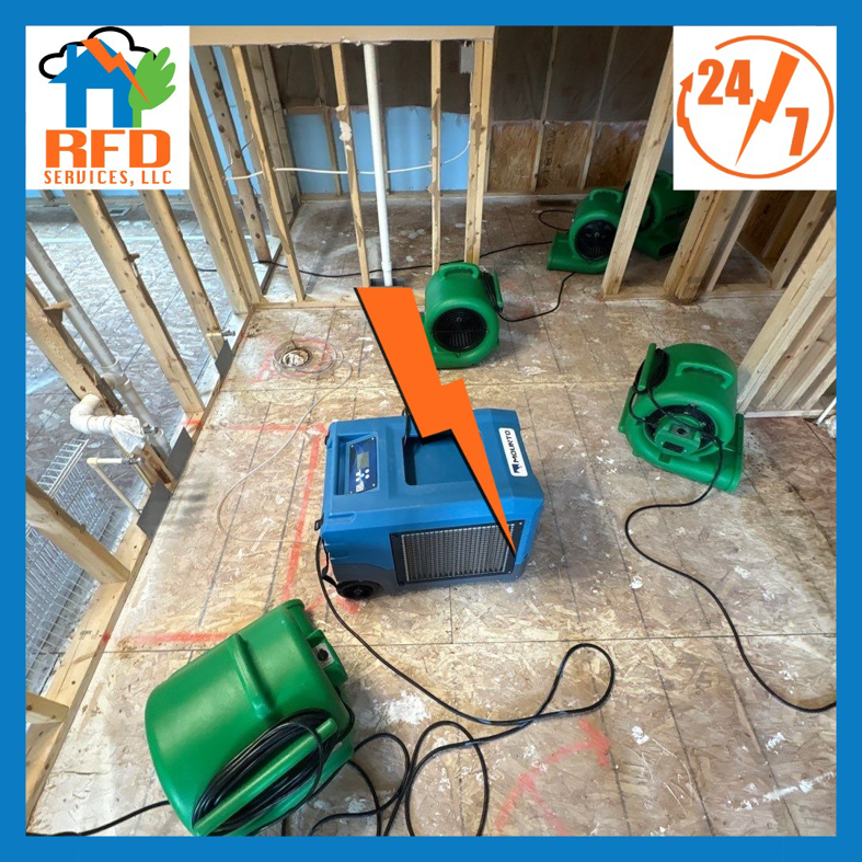 Drying equipment, including air movers and a dehumidifier, in a room with exposed studs by RFD Services in Akron, OH.