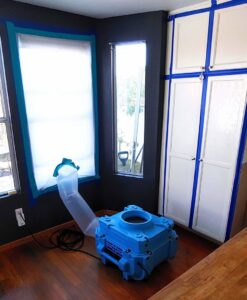 Water damage drying equipment with a flexible duct and taped window by Risk Free Serv Water Damage Repair San Diego, CA