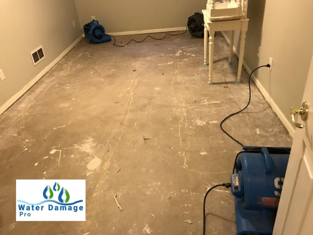 Air movers and drying equipment set up in a water-damaged room with removed baseboards by Water Damage Pro in Minneapolis, MN