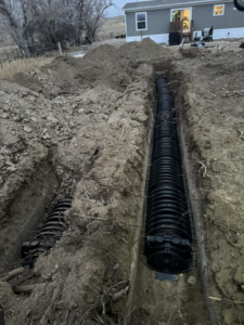 Dual drainage systems being installed in trenches near a house by MP-X LLC Excavation and Construction in Riverton, WY