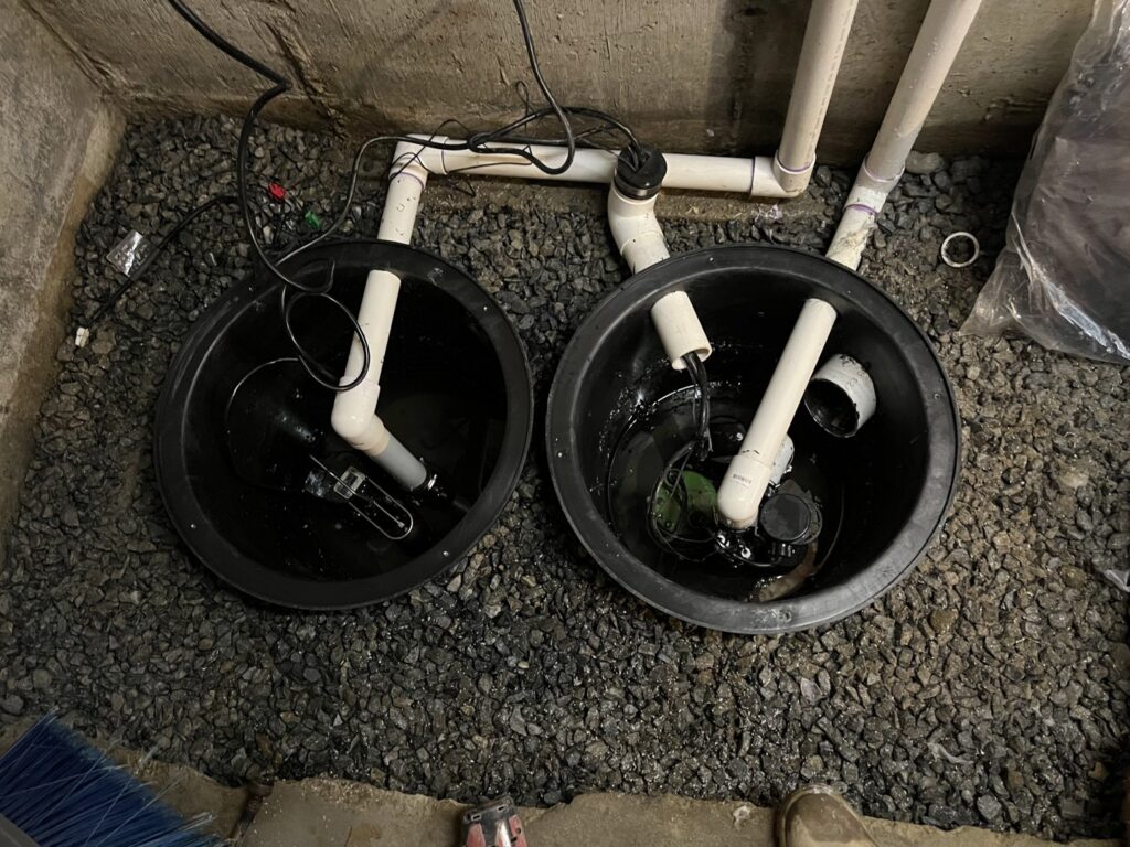 A dual sump pump system installed in a basement by EFFECTIVE WATERPROOFING in Worcester, MA.