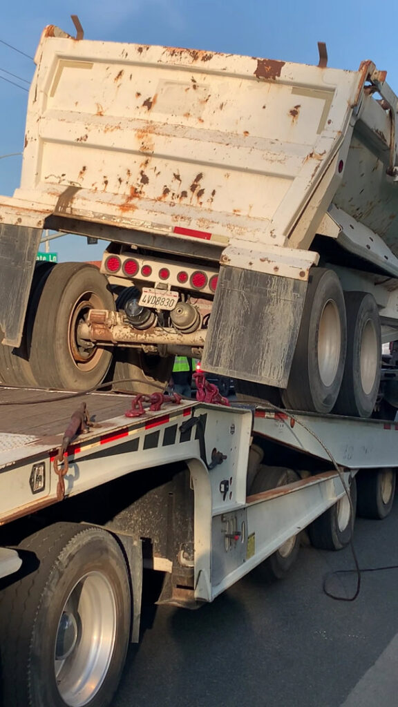 Affordable Towing LLC transporting a dump truck on a flatbed trailer in Anaheim, CA.
