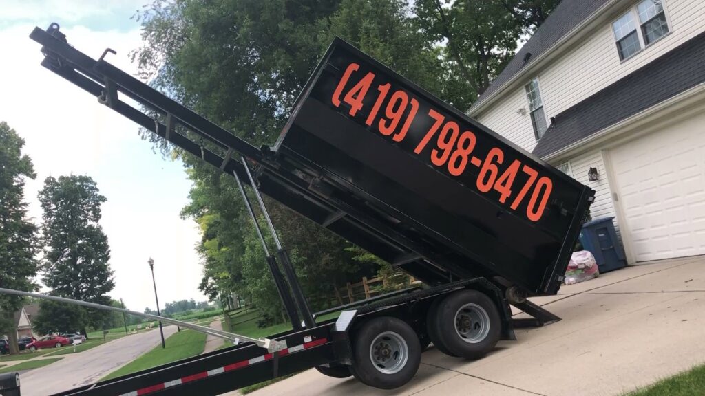 A black dumpster on a trailer being tilted, ready for rental or debris removal by Just Take It, LLC. in Yorba Linda, CA.