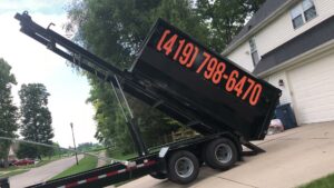 A black dumpster on a trailer being tilted, ready for rental or debris removal by Just Take It, LLC. in Yorba Linda, CA.