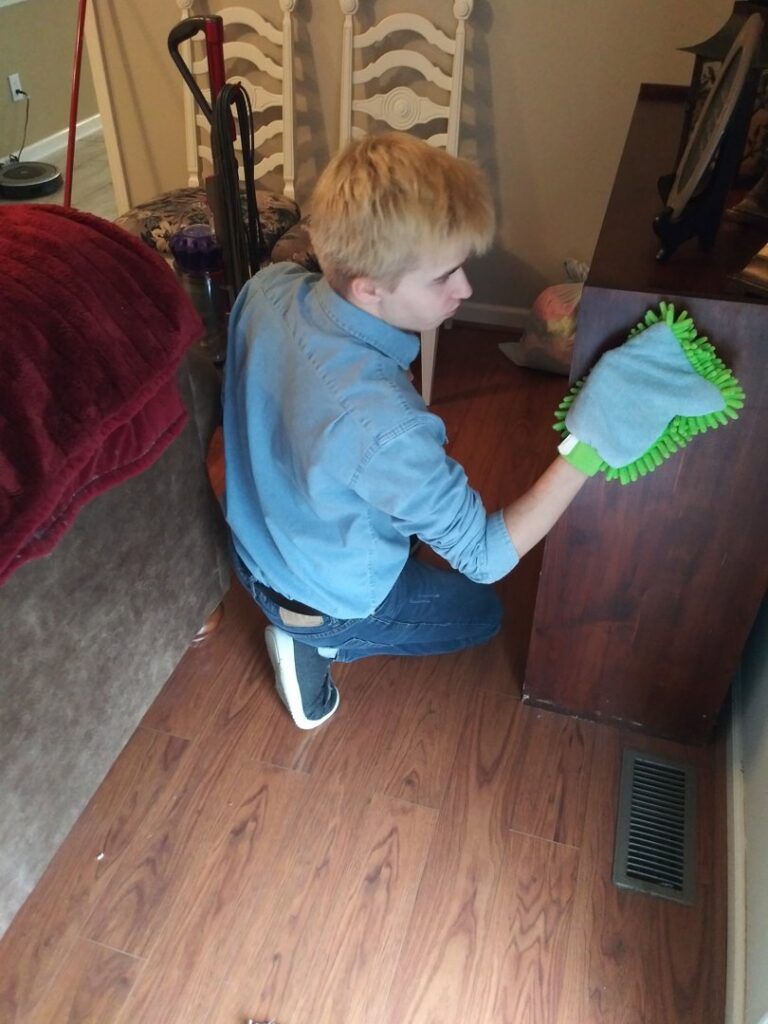 A cleaner dusting wooden furniture in a home by RJ Cleaning Services in Richmond, KY