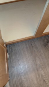 A dusty floor area under a kitchen cabinet, showing a spot ready for deep cleaning by On Point Cleaning Authority in Dayton, OH.