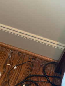 A dusty hardwood floor and baseboard, showing an area ready for cleaning by The Guzman Cleaning Service LLC in San Jose, CA.