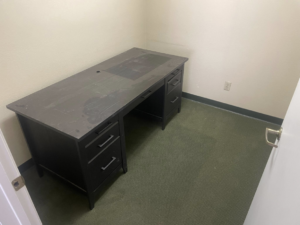 A dusty office desk in a small room before professional cleaning by Sister cleaning consultant in Fresno, CA.