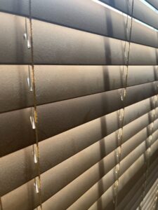 Close-up of dusty window blinds, highlighting an area requiring cleaning services from JLJ Sister's Cleaning & More in Lexington, KY.