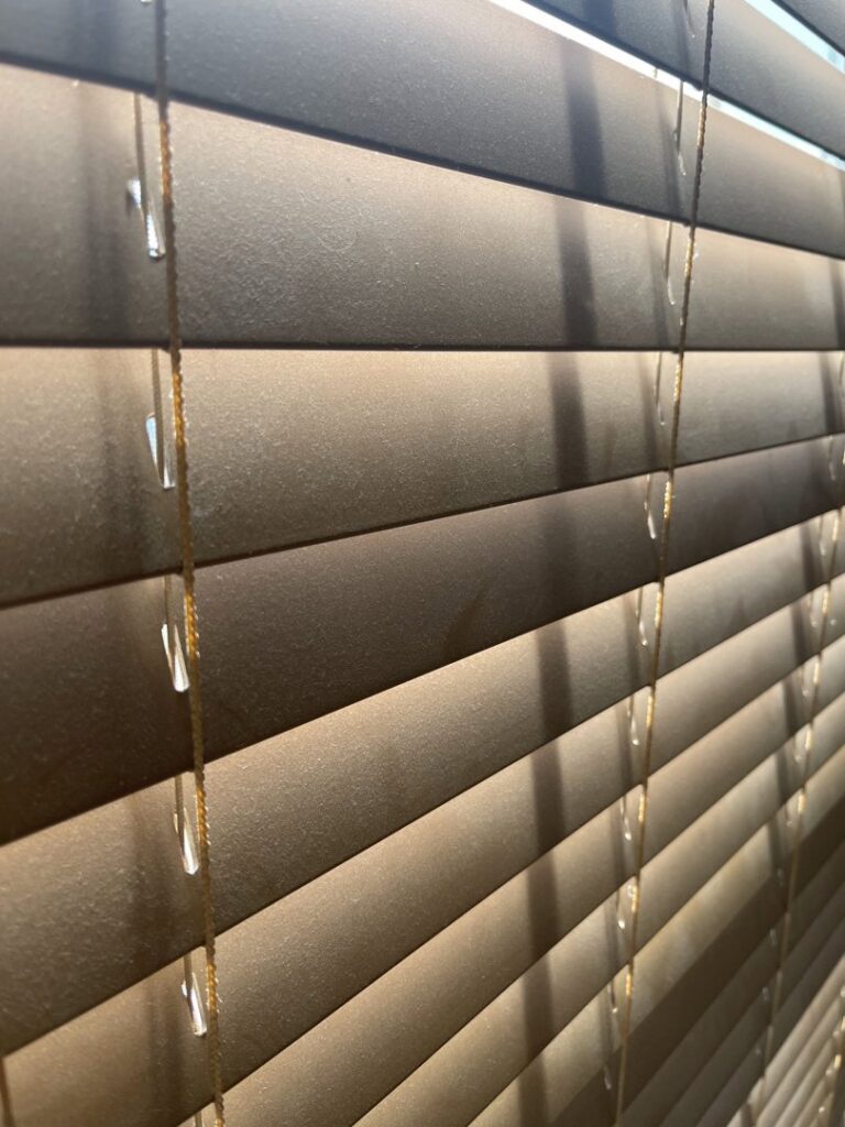 Close-up of dusty window blinds, highlighting an area requiring cleaning services from JLJ Sister's Cleaning & More in Lexington, KY.