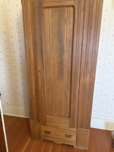 A tall wooden cabinet door showing dust and discoloration, indicating a need for cleaning by Clean & Clear Pros LLC in Timm Place, USA.