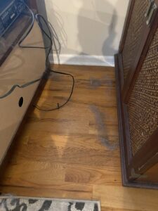 A dusty wooden floor with lint and debris, showing an area before house cleaning by Cuse Cleaning in Syracuse, NY.