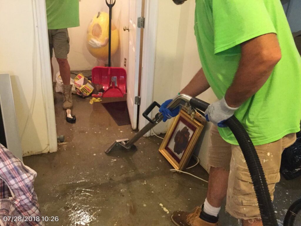 Servpro employee extracting standing water from a concrete floor in a basement in Jersey City, NJ.