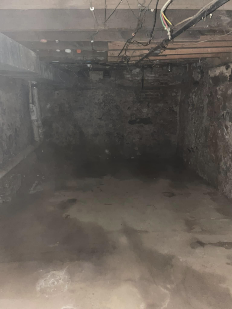 An empty basement showing rough walls and floor, indicating demolition preparation by Identical Demolition LLC in Philadelphia, PA.
