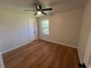 A freshly cleaned, empty bedroom with wooden floors and a ceiling fan, showcasing Krys Cleaning's work in Oklahoma City, OK.