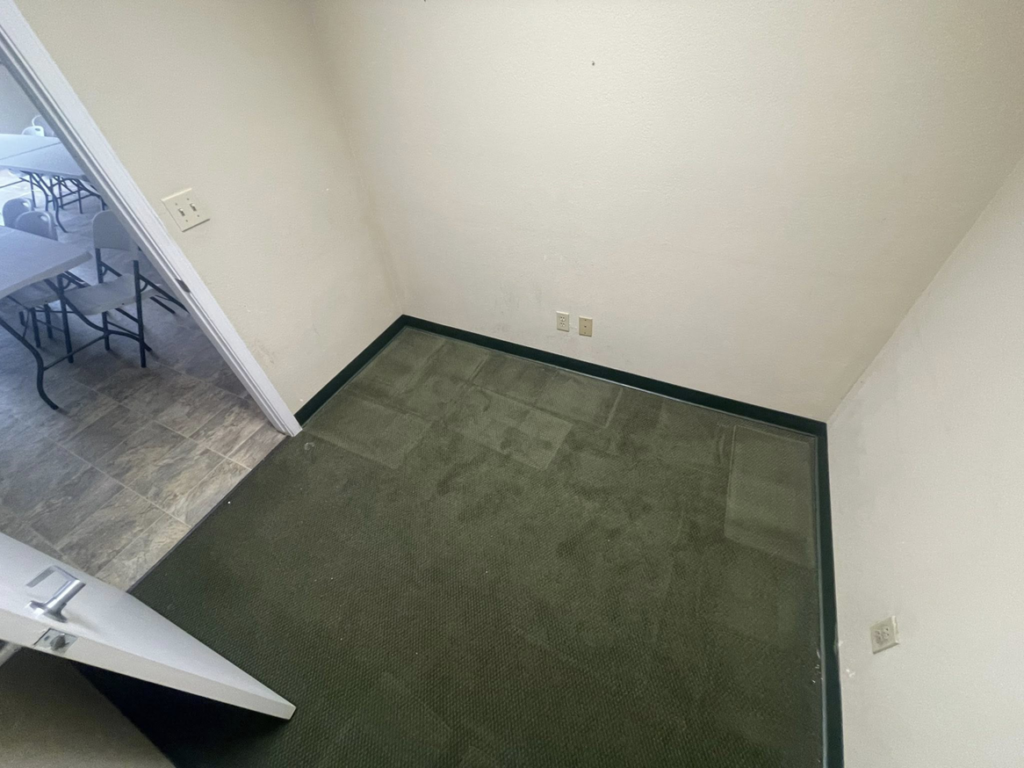 An empty, thoroughly cleaned room with green carpet, showcasing the results from Sister cleaning consultant in Fresno, CA.