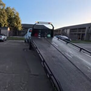 An empty flatbed tow truck parked in a lot, ready for a towing service job by Fort Benning Towing in Columbus, GA