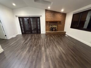 A spacious, empty living room with hardwood floors and a brick fireplace, showcasing a clean space by Quesada's cleaning services llc in Seattle, WA.