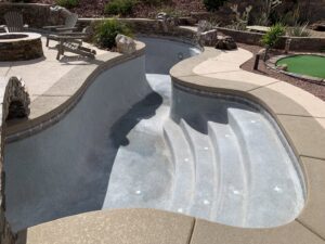An empty residential pool with steps and surrounding landscaping, ready for service by Pool Tile Cleaning Vegas in Las Vegas, NV.