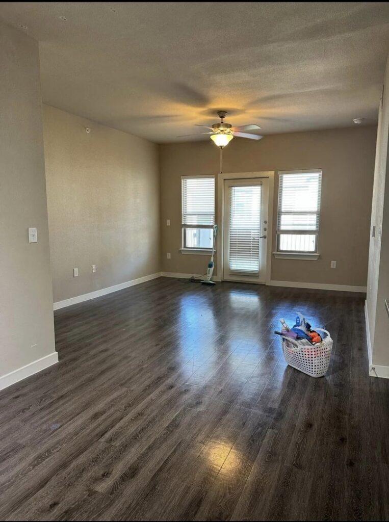 An empty room with hard floors, a cleaning caddy, and a mop, indicating professional house cleaning in progress by Estela's Cleaning Service's in Lake Elmo, MN.