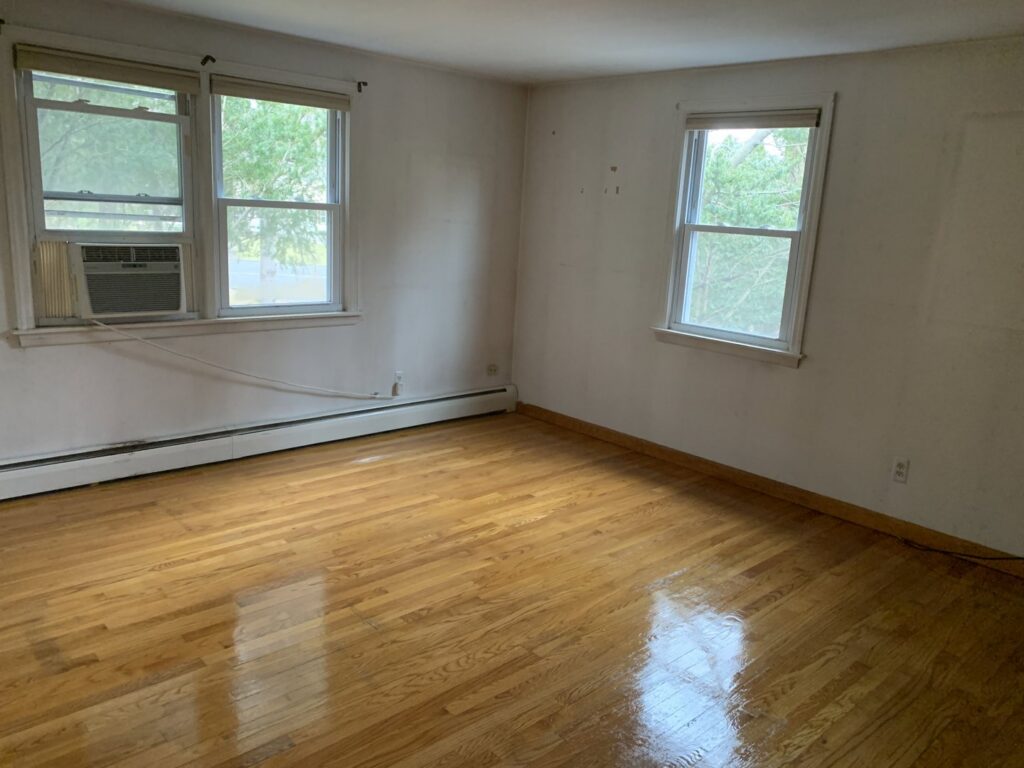 A sparkling clean empty room with shiny hardwood floors after a professional cleaning by Maids & Multi Services by Landry, LLC in Bristol, CT.