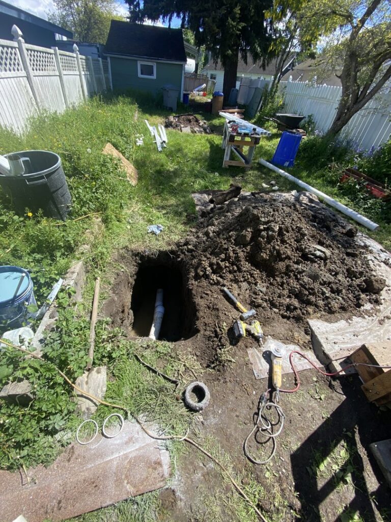 An excavated area with a pipe in a hole, indicating water damage repair or drain service by DNA Drain Cleaning & Sewer in Tulalip, WA.
