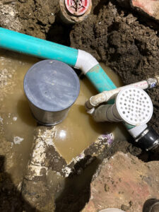An excavation site with pipes submerged in muddy water, showing a water damage repair by Mr. Rooter Plumbing of Youngstown, OH.