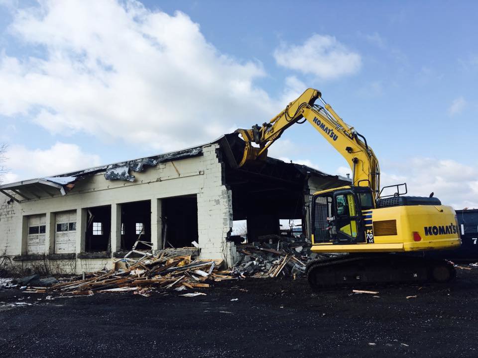 A Komatsu excavator actively demolishing the exterior of a building for Orion Demolition & Environmental Services, LLC in Albany, NY.