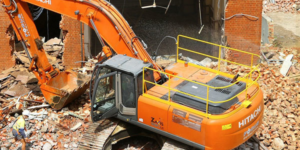 A large excavator demolishing a brick building, surrounded by rubble, by Youngstown Pro Demolition Services in Youngstown, OH.