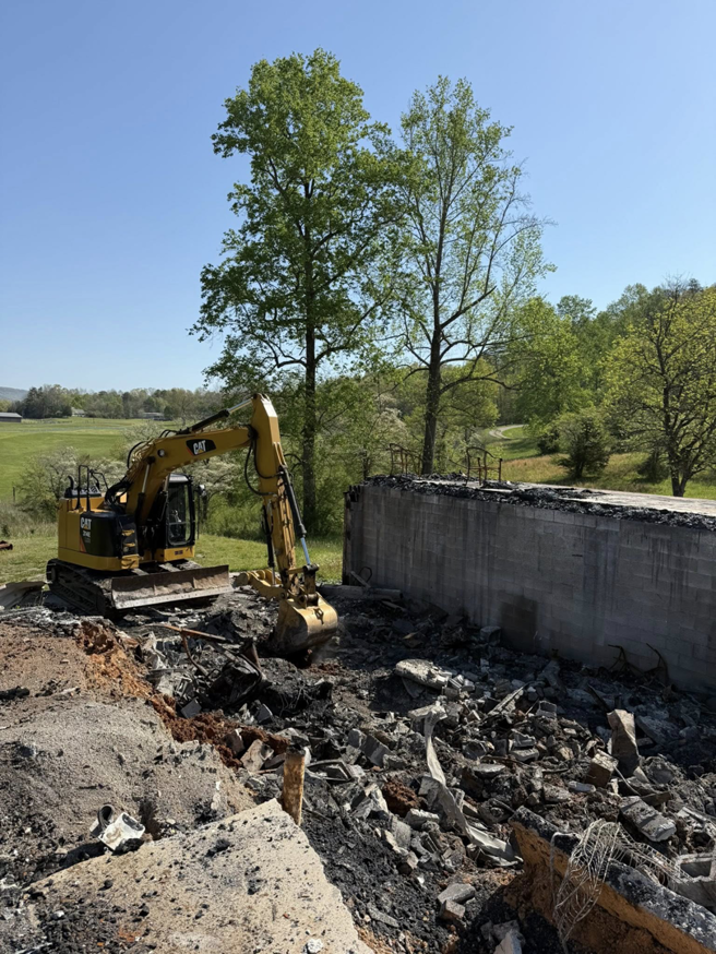 An excavator demolishing a concrete structure at a job site for Pro Dumpster Rentals in Chattanooga, TN.