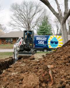 An excavator digging a trench for water line repair by Bright Side Plumbing in Overland Park, KS.