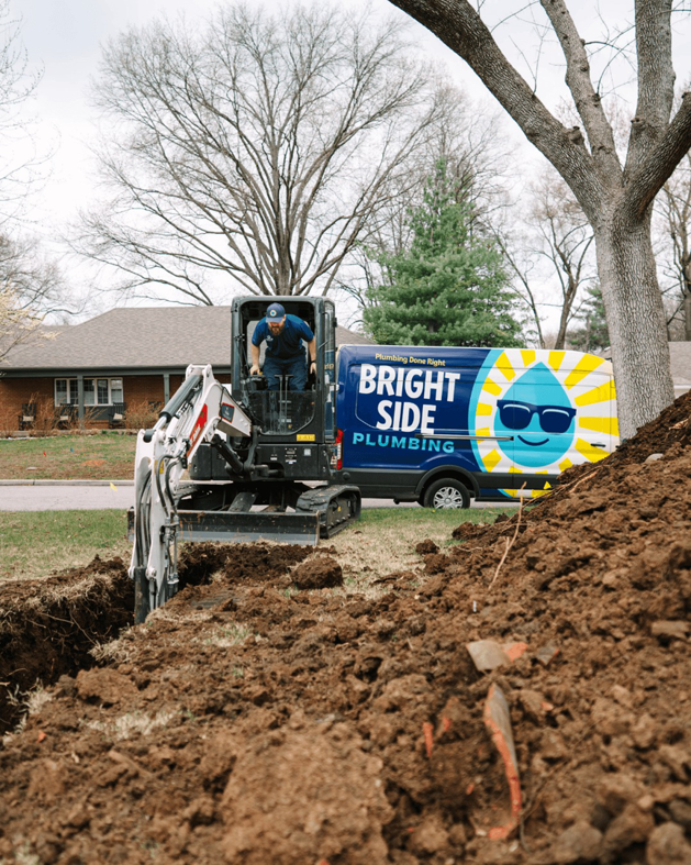 An excavator digging a trench for water line repair by Bright Side Plumbing in Overland Park, KS.