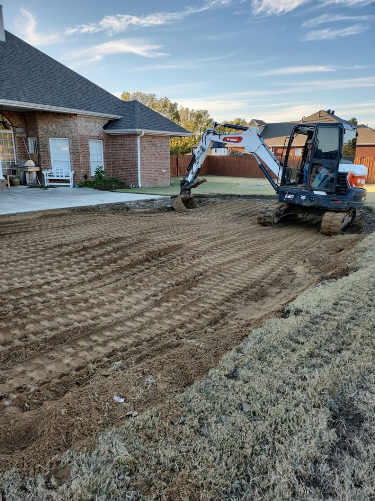 An excavator actively grading land next to a residential house by East Shelby Demolition & Pool Removal in Olive Branch, MS.