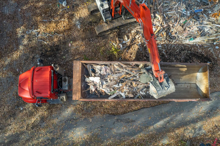 An excavator loading demolition debris into a dump truck, captured from an aerial view by Nuckles Services in Birmingham, AL
