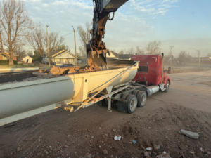 An excavator loading demolition debris into a dump truck, performed by Enfield Demolition & Excavation LLC in Enid, OK.