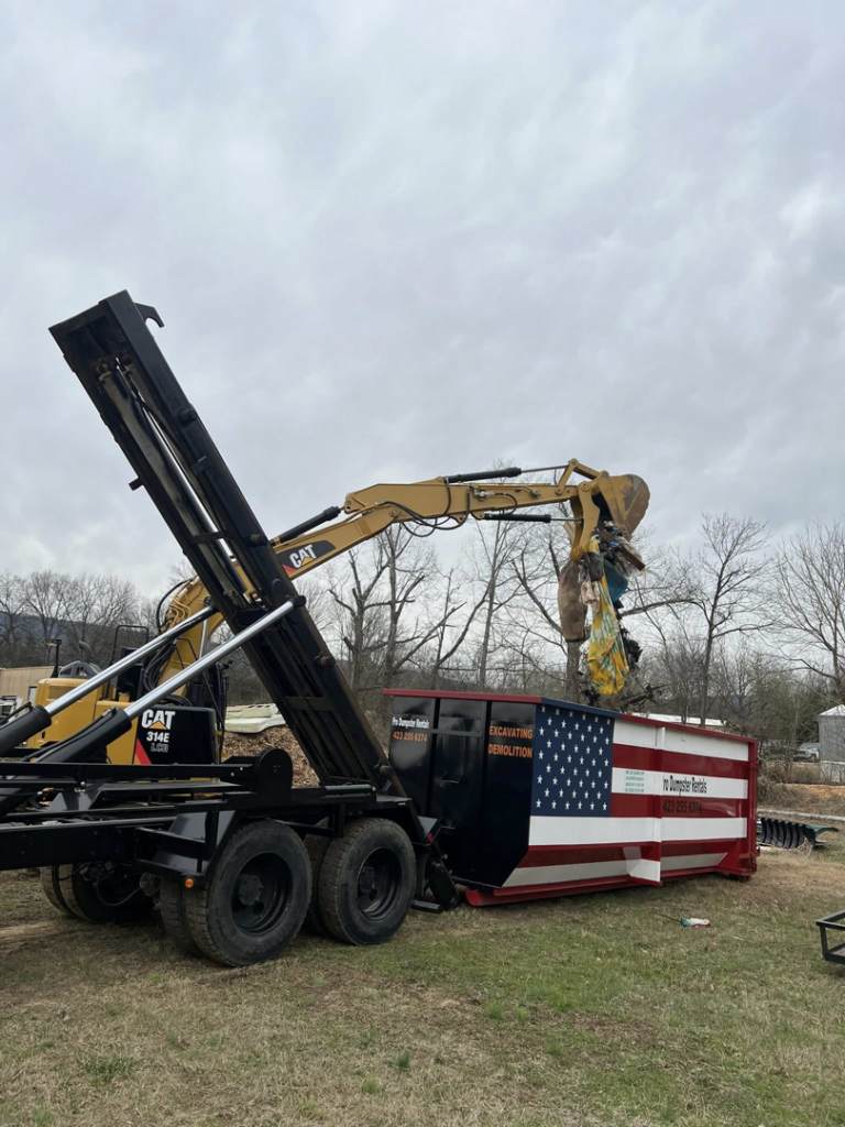 An excavator loading demolition debris into a Pro Dumpster Rentals container in Chattanooga, TN.