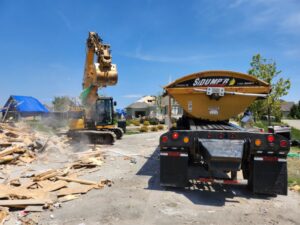 An excavator loading demolition debris into a large trailer at a job site for Allis Demolition & Hauling LLC in Omaha, NE