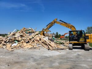 An excavator moving a large pile of demolition debris at a job site for Allis Demolition & Hauling LLC in Omaha, NE