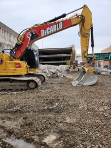An excavator from DeCarlo Demolition Company working on a demolition site in Des Moines, IA.