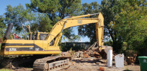 A large yellow excavator on a demolition site with debris, handled by Torrado Demolition in Houston, TX.