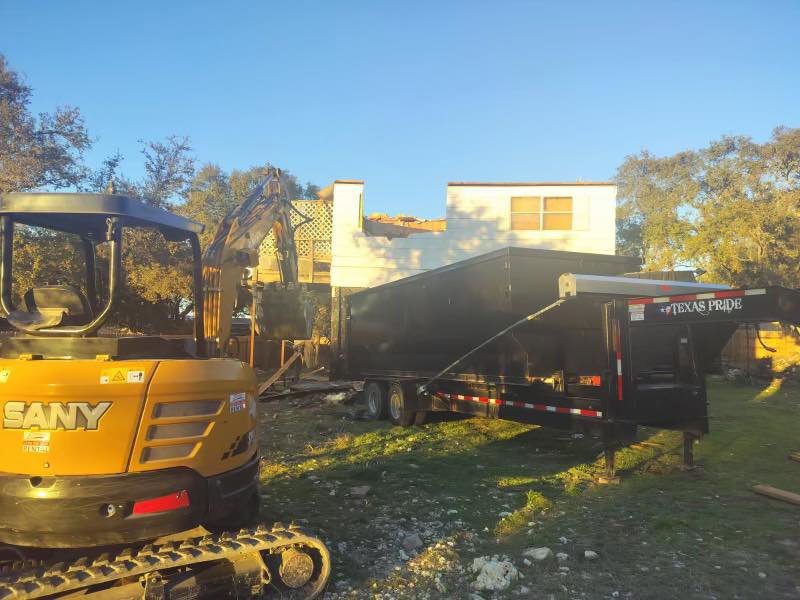 A small excavator and trailer at a partial house demolition site by San Antonio Demolition Pros in San Antonio, TX.