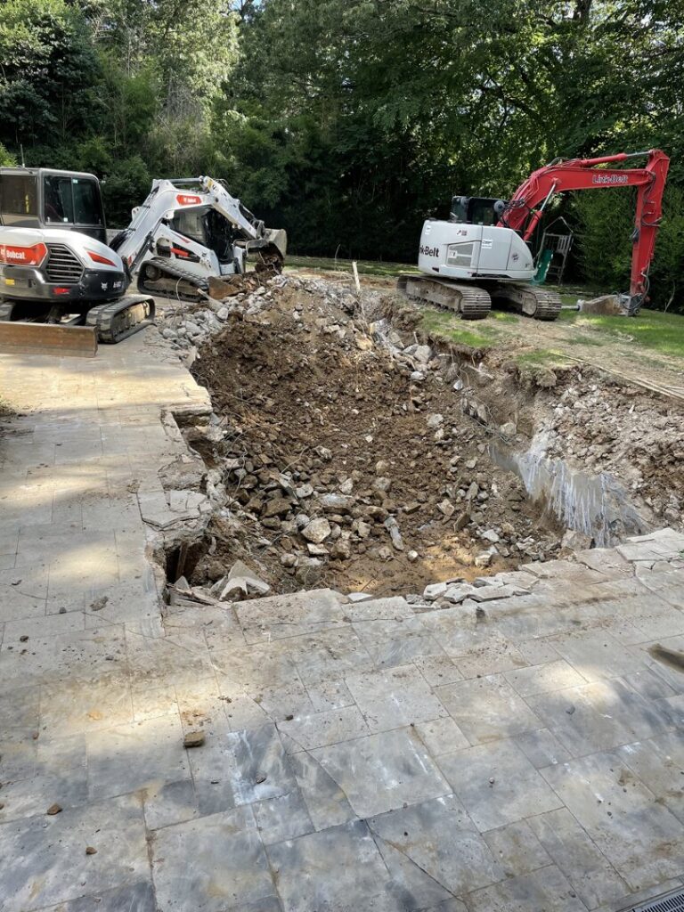 Two excavators working on a large pile of dirt and debris from a pool removal project by East Shelby Demolition & Pool Removal in Olive Branch, MS.